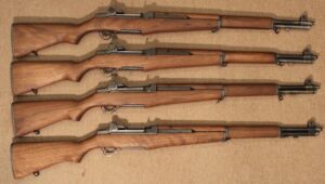 Four wooden rifles aligned on a surface.