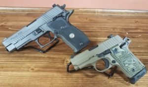 Two handguns placed on a wooden surface, one black and one tan.